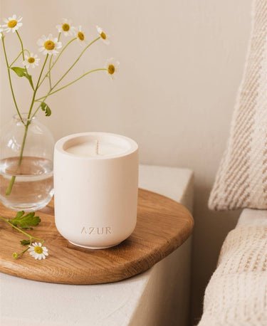 Vela Spicy Spirit de soja y aceites esenciales de Azur Natural Bodycare, sobre una mesa auxiliar junto a flores