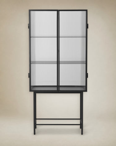 Vitrina de Ferm Living: vitrina alta negra frontal, dos puertas de vidrio y dos baldas interiores.