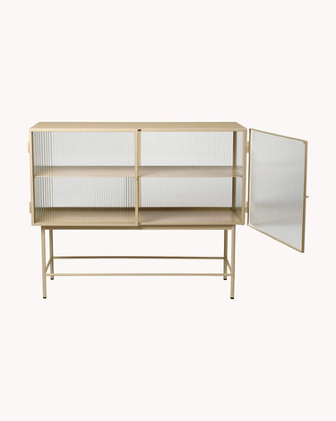 Vista de una de las vitrinas de Ferm Living, con la puerta derecha abierta y una balda metálica beige.