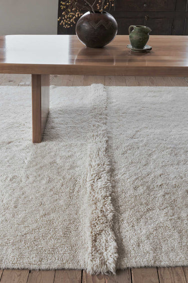 Alfombra Tundra blanca de 80 × 140 cm en un interior natural