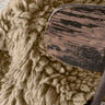 Alfombra Woolly beige colocada junto a una cama